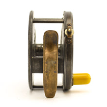 Load image into Gallery viewer, Antique brass faced fishing reel with a center decorative disc and a yellow handle, showing signs of aging and use. 1906 brass faced perfect against a white background