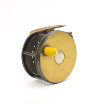 Load image into Gallery viewer, Antique brass faced fishing reel with a center decorative disc and a yellow handle, showing signs of aging and use. 1906 brass faced perfect against a white background