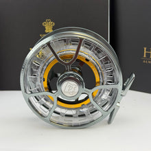 Load image into Gallery viewer, Picture of a hardy aversion lightweight large arbour fly reel looks new and unused with original hardy case behind on a white background