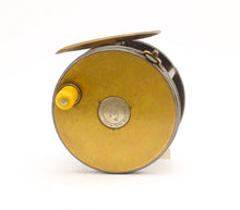 Load image into Gallery viewer, Antique brass faced fishing reel with a center decorative disc and a yellow handle, showing signs of aging and use. 1906 brass faced perfect against a white background